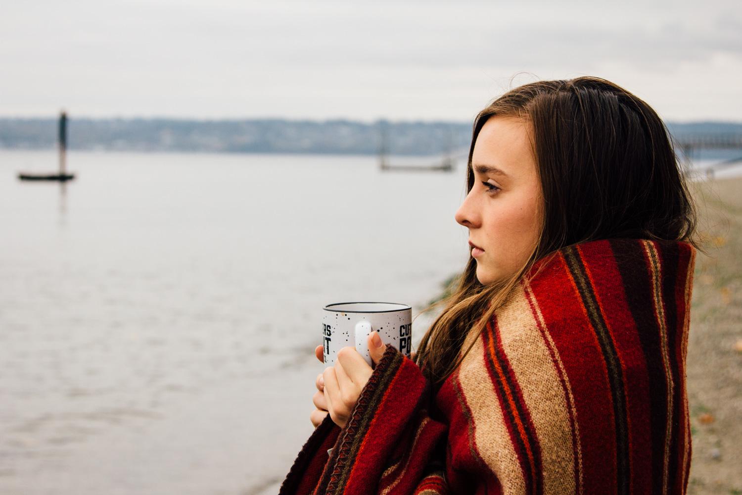 Young woman wrapped in a blanket looking at the Puget Sound