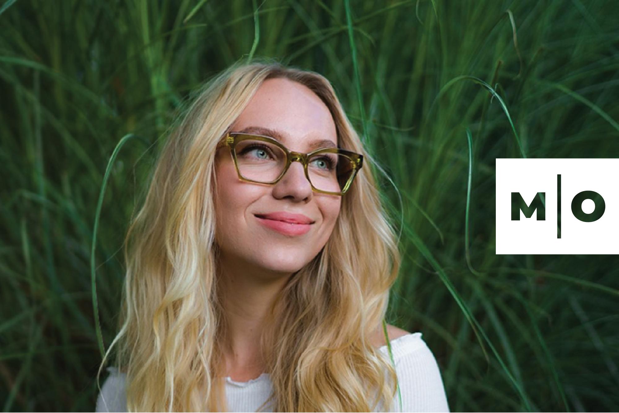 Woman wearing Market Optical glasses and standing in front of a bush